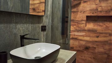 A bathroom with a large, oval-shaped vessel sink, a mirror, and a wooden wall.