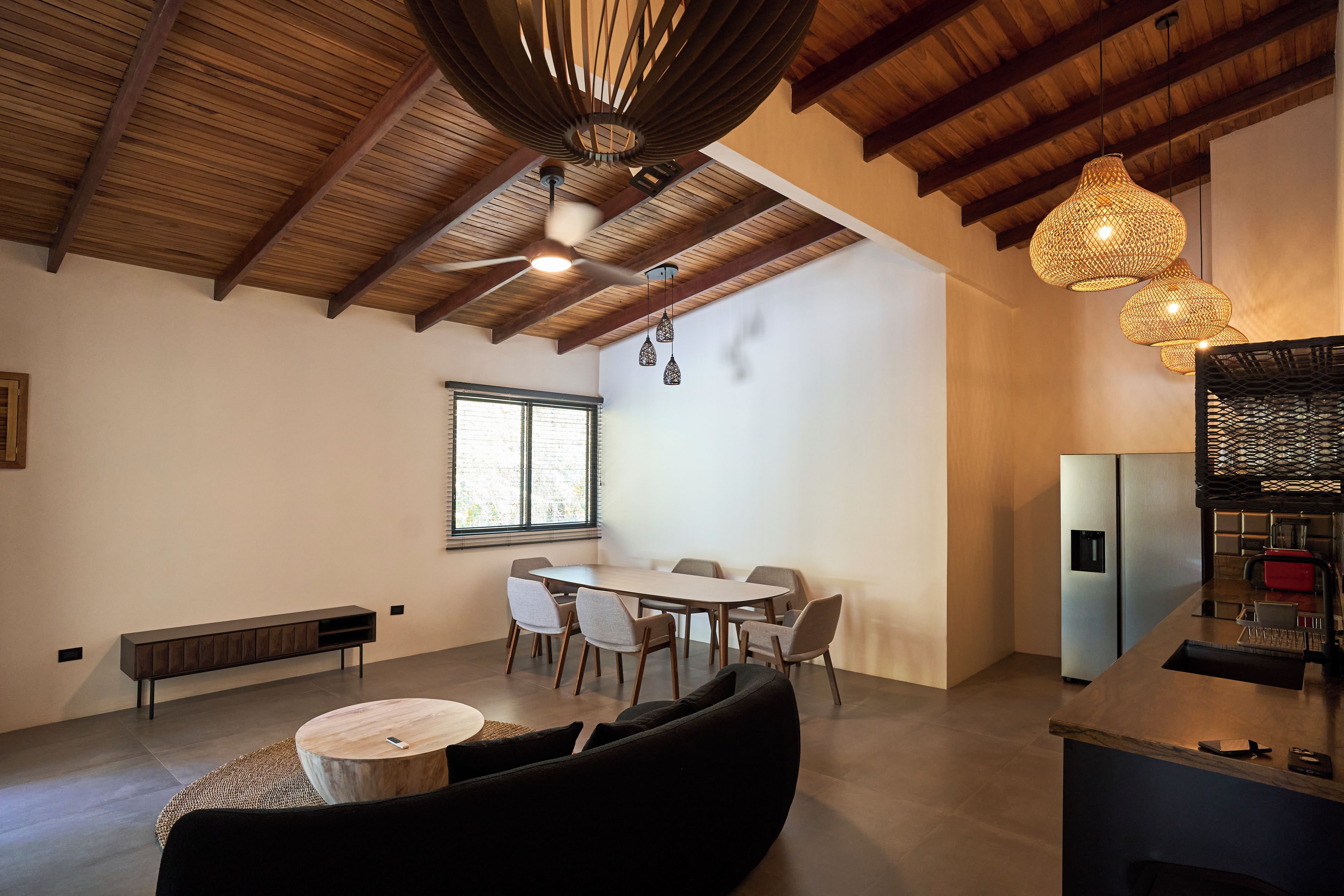 Une cuisine moderne dotée d’un réfrigérateur encastré, d’un coin repas avec une table ronde et des chaises, et d’un ventilateur de plafond.