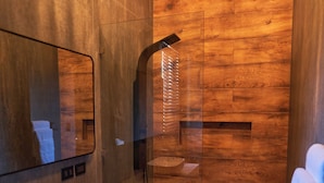 A modern bathroom with a large mirror, a sink, and a shower area. - Desiree Luxury Apartamentos (Malpaís)