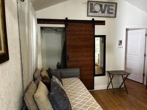 A bedroom with a bed, a wooden sliding door, a small table, and a mirror. - Cozy 2-Bedroom Retreat in Beautiful Delray Beach (Delray Beach)