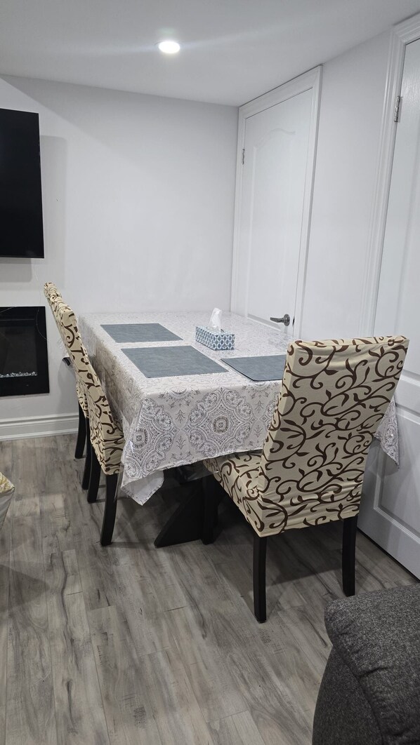 A dining area with a table covered in a patterned tablecloth, surrounded by chairs with a matching design.