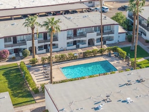 A multi-story hotel with a rooftop pool, palm trees, and a parking area. - Litchfield Park Getaway and Pool 2BR Condo (Litchfield Park)