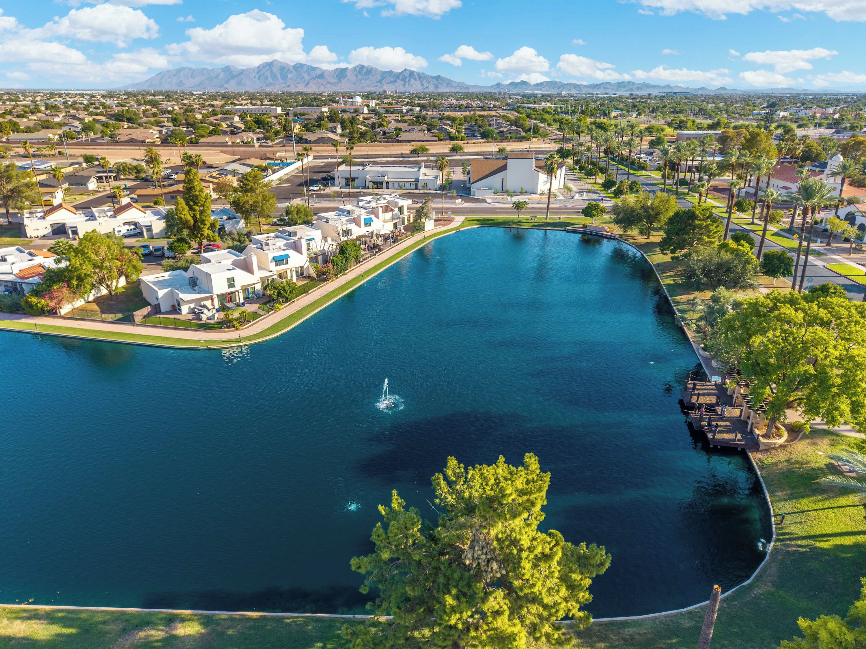A large body of water with a fountain, surrounded by residential buildings and greenery.