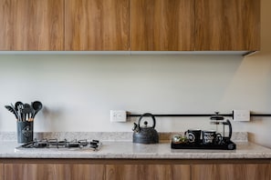 A kitchen with wooden cabinets, a gas stove, a kettle, a coffee maker, and a utensil holder. - 2 bedrooms, 2 bathrooms | Polanco | Relax (Ciudad de México)