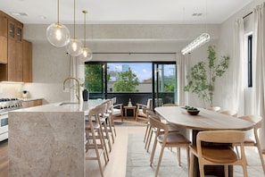 A modern kitchen with a marble island, wooden cabinets, and pendant lighting. - 6 Bedrooms with Hot Tub, Rooftop, Garage + near Downtown (Nashville)