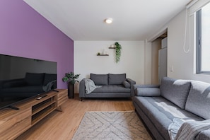 A modern living room with a flat-screen TV, a grey sofa, a wooden coffee table, and a patterned rug. - 3 bedrooms | Polanco | Relax (Ciudad de México)