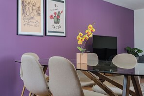 A dining area with a glass table, beige chairs, and a purple wall. - 3 bedrooms | Polanco | Relax (Ciudad de México)