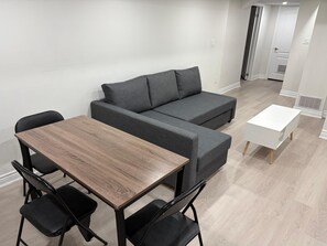 A modern living room with a sofa, a coffee table, and two chairs. - Charming Basement Suite | Near Airport & Wonderland (Brampton)