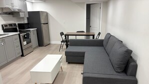 Et moderne køkken med spiseplads, en grå sofa og et hvidt sofabord.