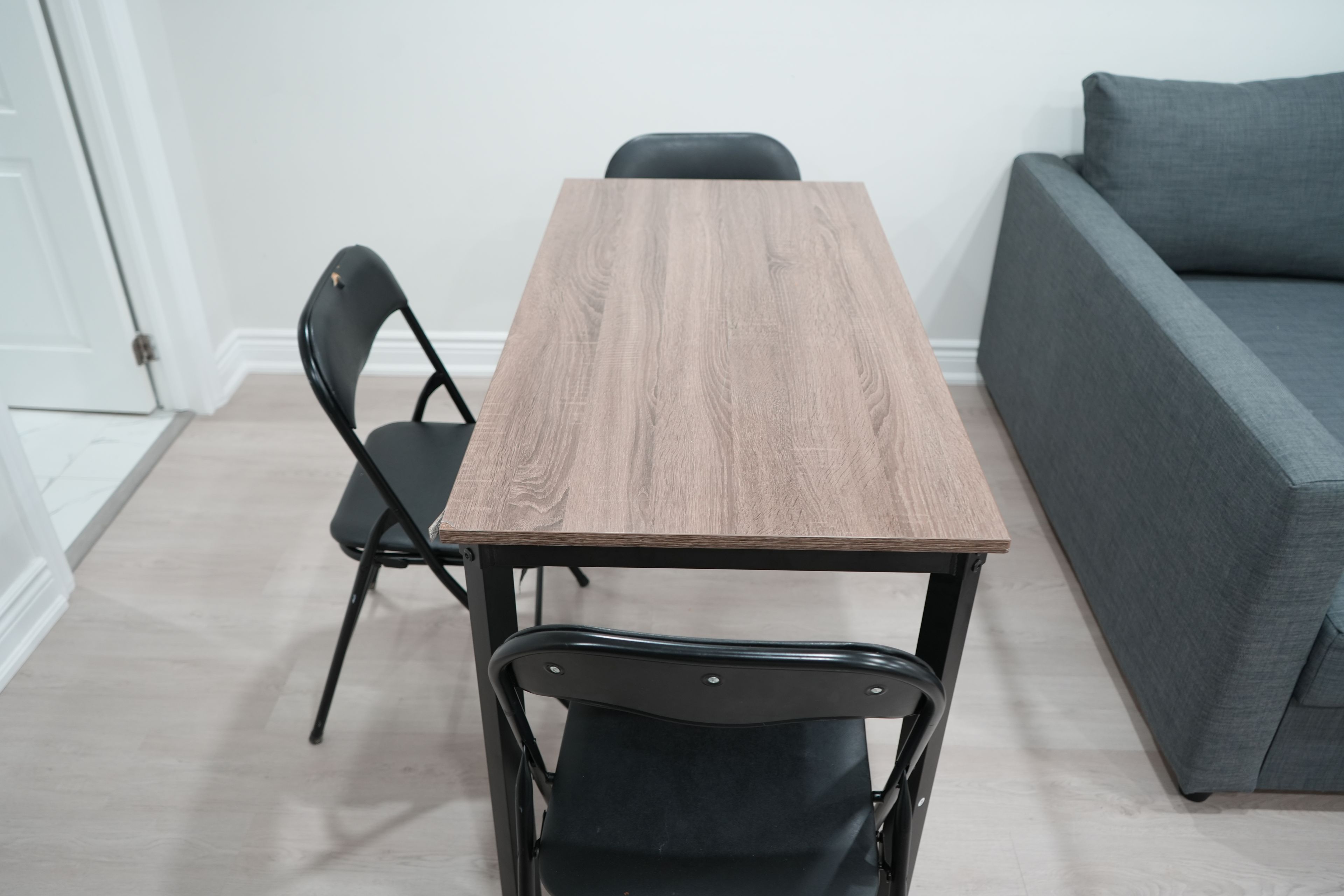 A rectangular wooden table with a black metal frame, accompanied by two black chairs.