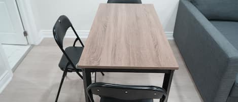 A rectangular wooden table with a black metal frame, accompanied by two black chairs.