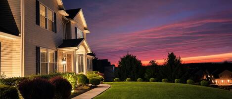 A two-story residential house with a well-maintained lawn and a driveway leading to the entrance.