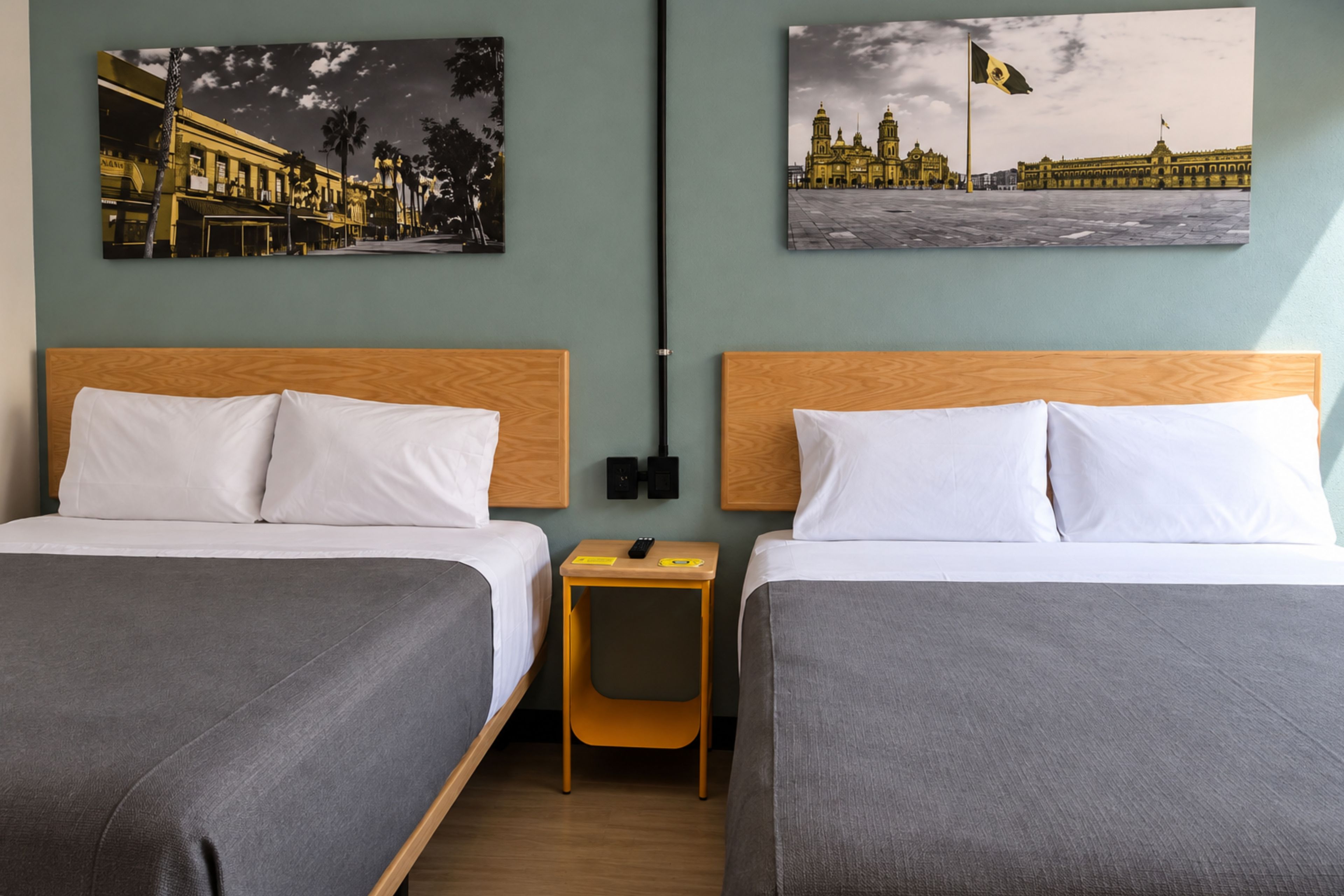 Une chambre d’hôtel avec deux lits, une table de chevet et deux lampes fixées au mur.