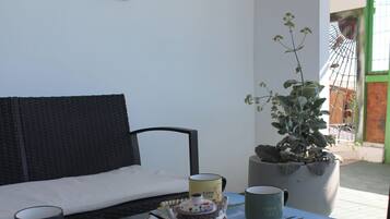 A room with a black sofa, a table with a teapot, cups, and a potted plant.