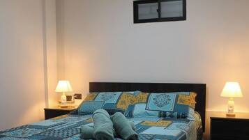 A bed with a patterned bedspread, two bedside lamps, and a nightstand with a lamp.
