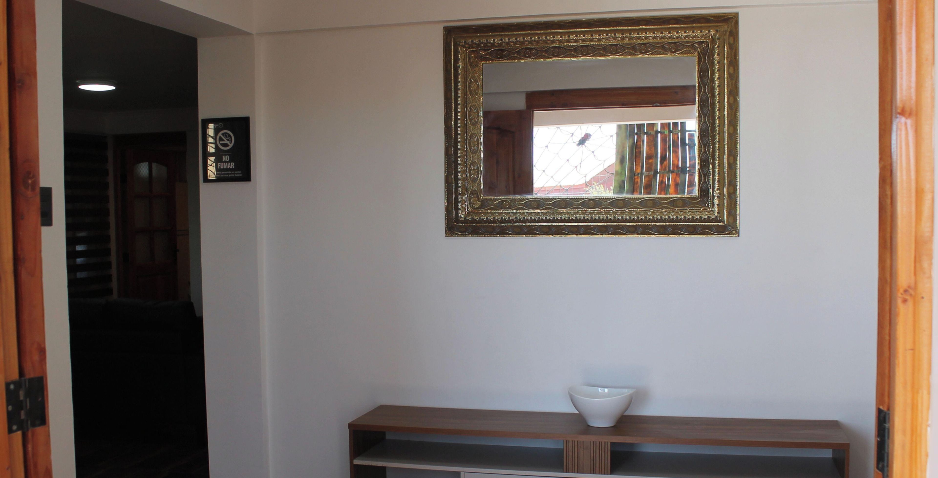 A room with a wooden console table, a white bowl, and a decorative mirror with an ornate frame.