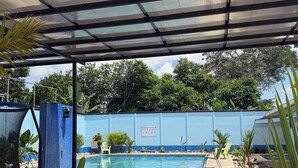 Un'area esterna coperta con piscina, posti a sedere e un muro blu con un cartello.