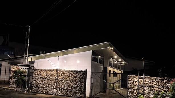 Una casa moderna con garage, muro in pietra e ingresso carrabile.