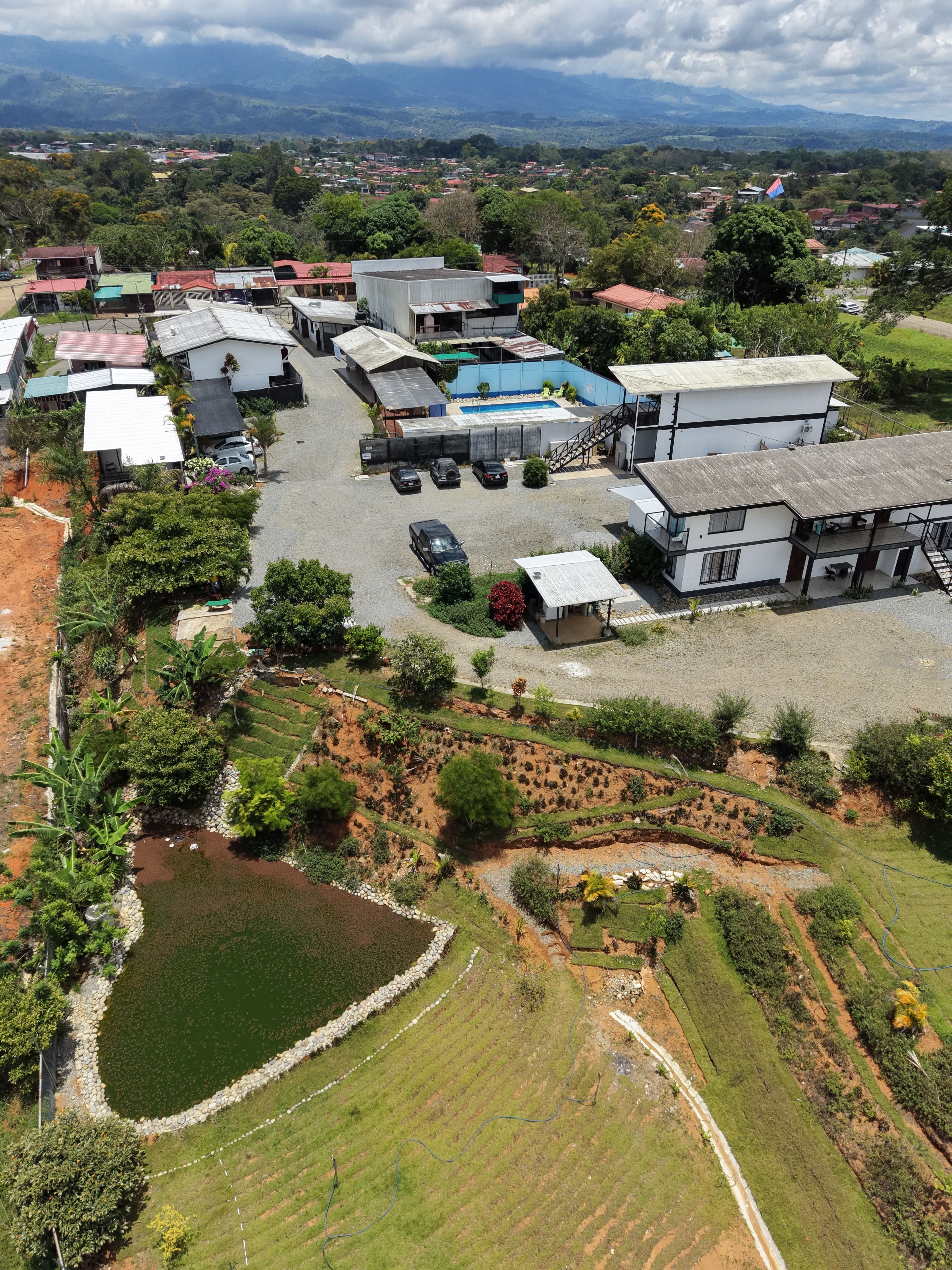 Un quartier résidentiel avec des maisons, une piscine et des champs en terrasses.