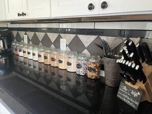 A kitchen counter with jars of snacks and a sign with a WiFi password.