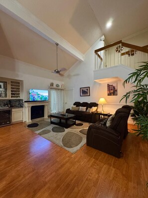 A spacious living room with a fireplace, a television, and a staircase leading to an upper level. - Central & Spacious 4-bedroom house in beautiful Houston with Central A/C (Houston)
