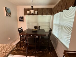 A dining area with a table, chairs, a chandelier, a clock, and a window with blinds. - Central & Spacious 4-bedroom house in beautiful Houston with Central A/C (Houston)