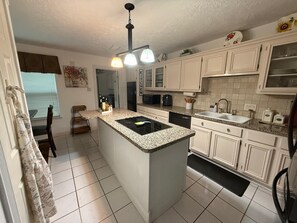 A kitchen with white cabinets, a granite countertop, a black stove, and a ceiling light fixture. - Central & Spacious 4-bedroom house in beautiful Houston with Central A/C (Houston)