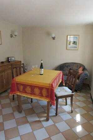 Ein Essbereich mit einem Tisch für zwei Personen, einer Weinflasche und einem Radio auf einem Schrank.