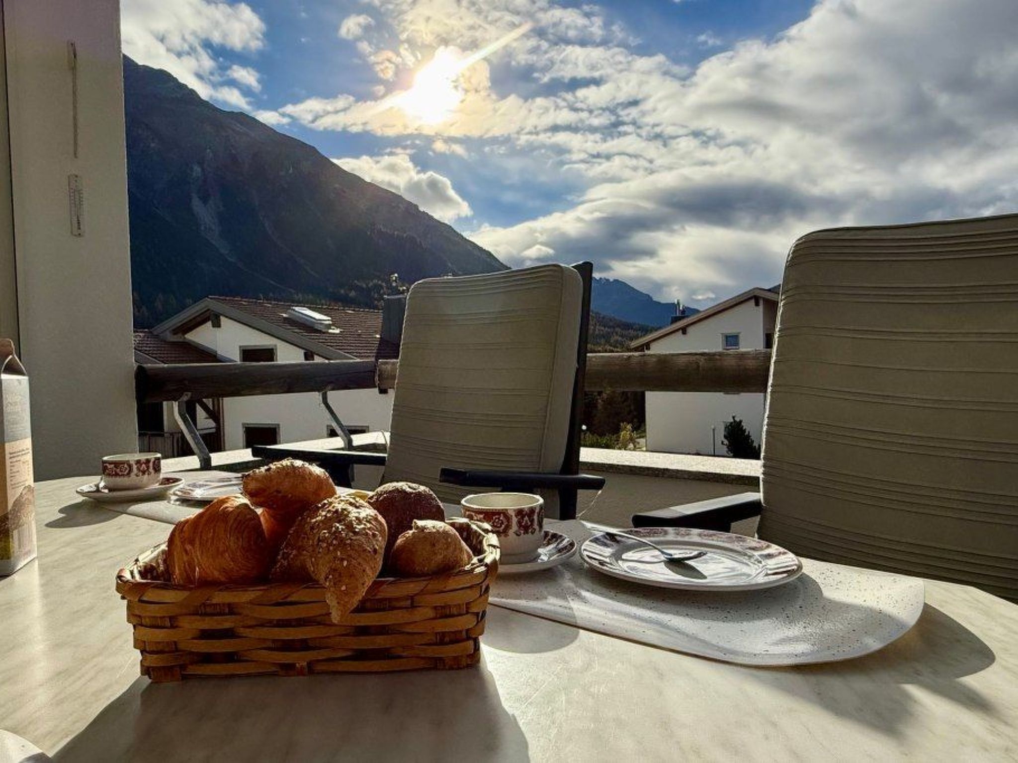 Une table avec un panier de pain et une tasse, donnant sur une montagne.