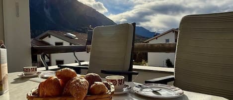 Une table avec un panier de pain et une tasse, donnant sur une montagne.