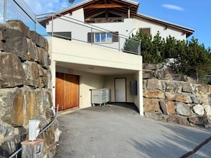 A two-story building with a stone facade, a wooden door, and a metal gate. - Fewoerholungpur (CharmingStay), (Lenzerheide), by Interhome (Lenzerheide)