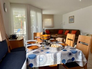 A dining area with a table set for a meal, featuring a patterned tablecloth and various dishes. - Fewoerholungpur (CharmingStay), (Lenzerheide), by Interhome (Lenzerheide)
