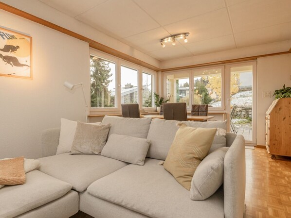 A modern living room with a sectional sofa, large windows, and a view of the outdoors.