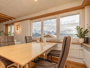 A conference room with a long table, chairs, and a view of mountains through large windows.