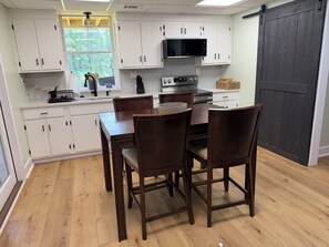 A kitchen with white cabinets, a microwave, a stove, and a dining table with chairs. - Cozy 1-bedroom apartment in great convenient location in Marietta, GA (Marietta)
