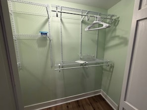 A room with a metal shelving unit against a light green wall, wooden flooring, and a white door. - Cozy 1-bedroom apartment in great convenient location in Marietta, GA (Marietta)