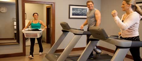 A fitness room with treadmills, a wall clock, and a framed picture.