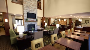 Un'hall d'albergo con zone relax, un camino, un bar e una televisione a parete.