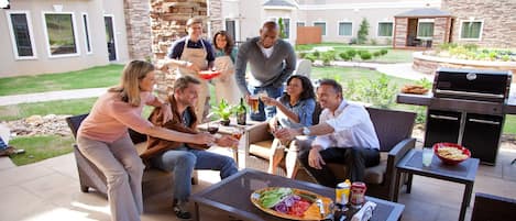 Un grupo de personas disfrutando de una comida al aire libre, con una parrilla y zona de comedor.