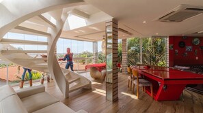 A modern interior with a spiral staircase, a red bar area, and a view of the outdoors. - Casa em Condom nio com Piscina e Sinuca em Itupeva (Itupeva)