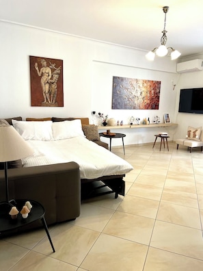 A modern bedroom with a bed, bedside tables, a TV, and artwork on the walls. - Elegant Apt 50meters Close Acropolis (Athina)