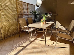 An outdoor patio with a table and chairs, a decorative fence, and potted plants. - Elegant Apt 50meters Close Acropolis (Athina)
