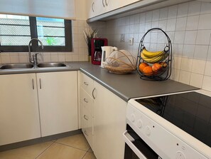 Een keuken met een fornuis, spoelbak en kastjes.