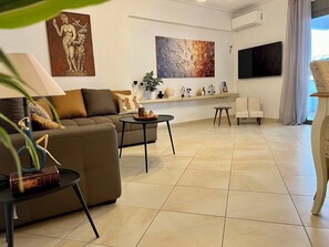 A modern living room with a sofa, coffee table, and a TV mounted on the wall. - Elegant Apt 50meters Close Acropolis (Athina)