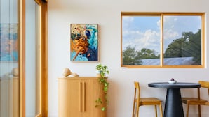 A room with a wooden cabinet, a round table with chairs, a potted plant, and a painting on the wall. - Luxe Farmhouse with Scenic Views and Cowboy Pool (Fayetteville)
