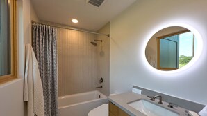 A modern bathroom with a bathtub, toilet, and sink. - Luxe Farmhouse with Scenic Views and Cowboy Pool (Fayetteville)