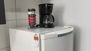 A white refrigerator with a coffee maker on top, a calendar, and a canister with labels. - Pearl Apartment (Sumaré)