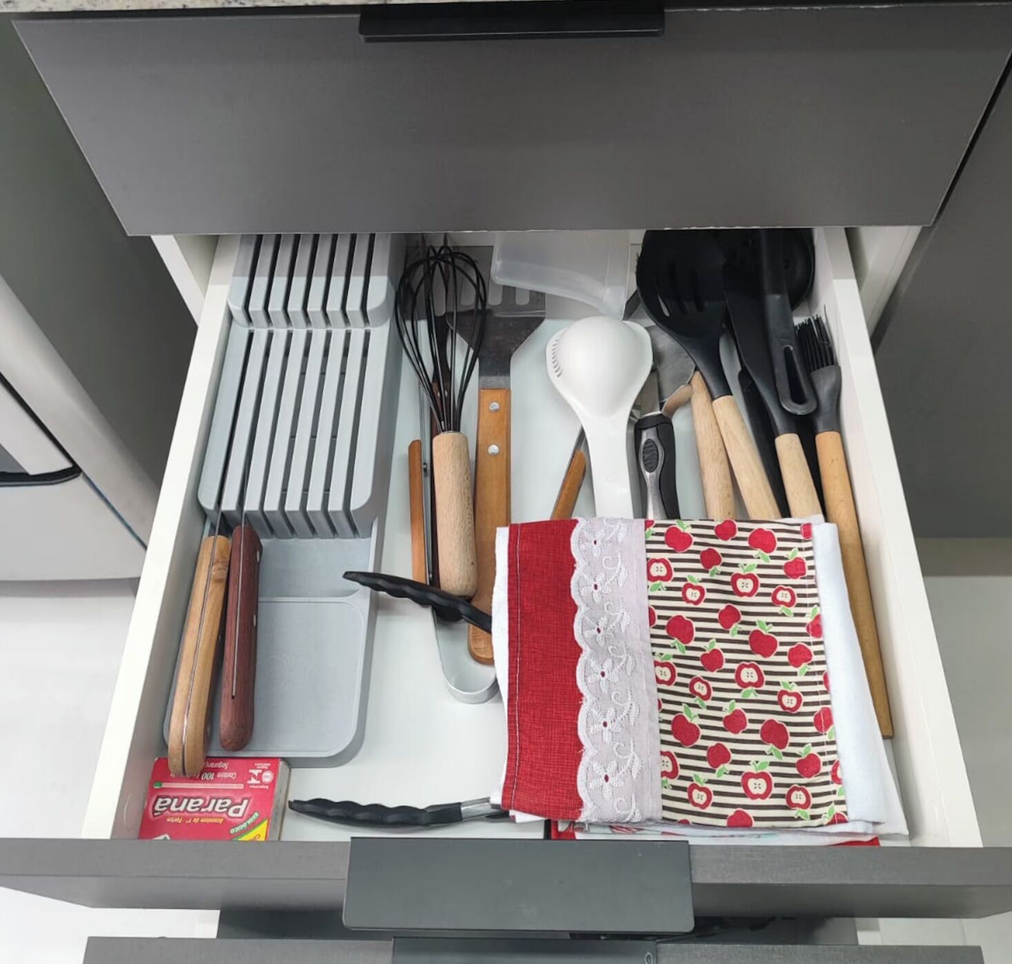 Un cajón con utensilios de cocina, incluyendo batidores, espátulas y una caja de pasta.