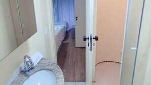 A bathroom with a sink, mirror, and shower area. - Apartamento Cristal Feirinha Liberade SP (São Paulo)