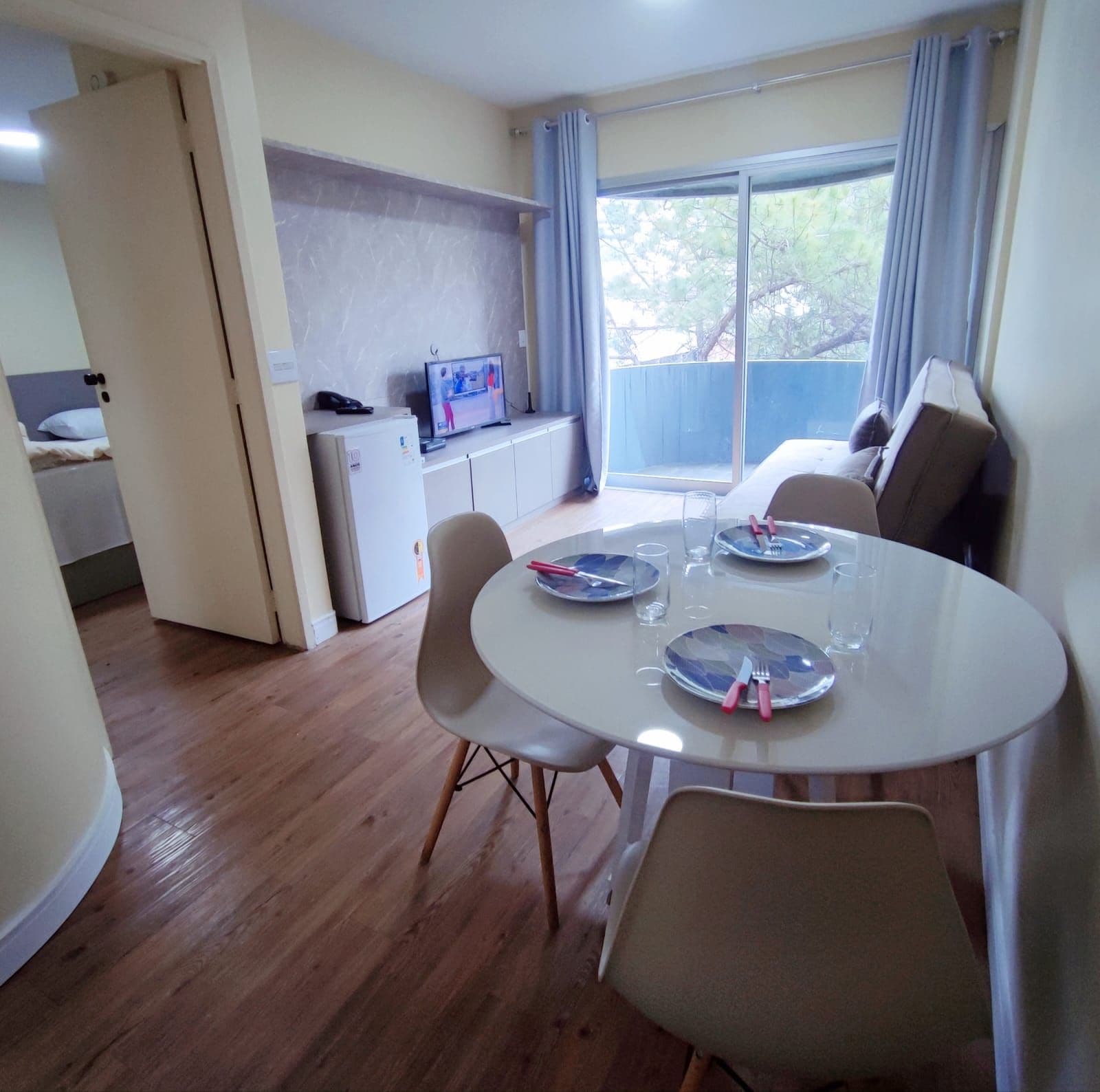 Un coin repas avec une table ronde, des chaises et un téléviseur posé sur un meuble.